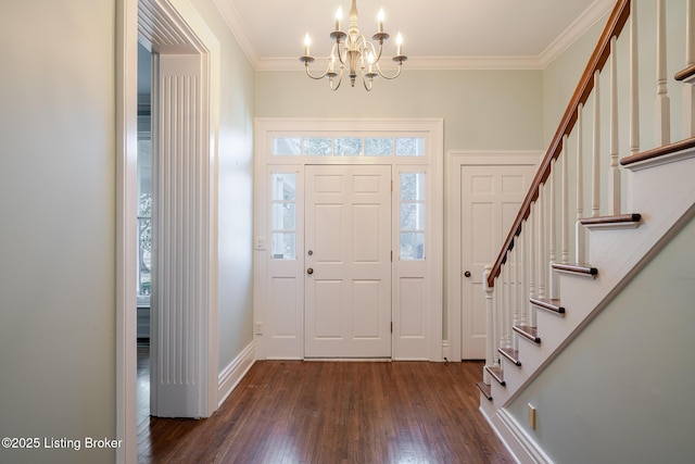 foyer entrance with baseboards, dark wood-style floors, ornamental molding, an inviting chandelier, and stairs