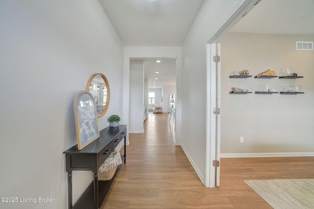 corridor featuring light wood finished floors, baseboards, visible vents, and recessed lighting