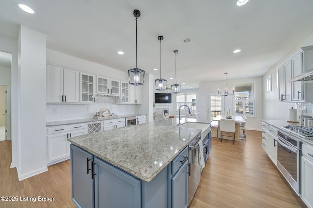 kitchen with light wood-style floors, white cabinets, stainless steel oven, and backsplash