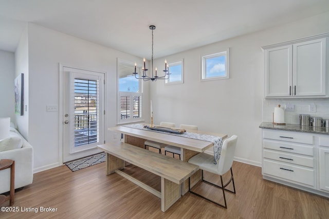 dining area with light wood-style floors, a notable chandelier, and baseboards