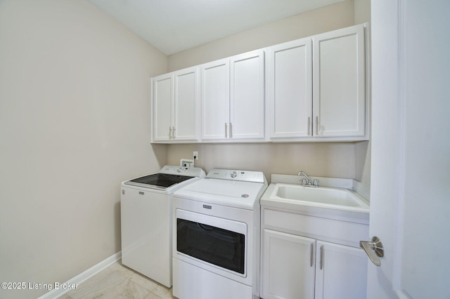 clothes washing area featuring a sink, washing machine and clothes dryer, cabinet space, and baseboards