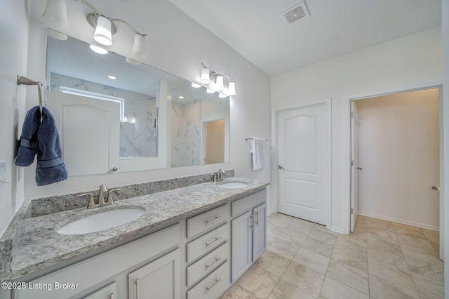 bathroom featuring marble finish floor, double vanity, a sink, and a marble finish shower