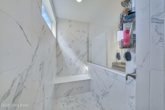 bathroom featuring a marble finish shower and tile walls