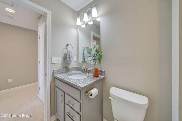 bathroom featuring toilet, baseboards, and vanity