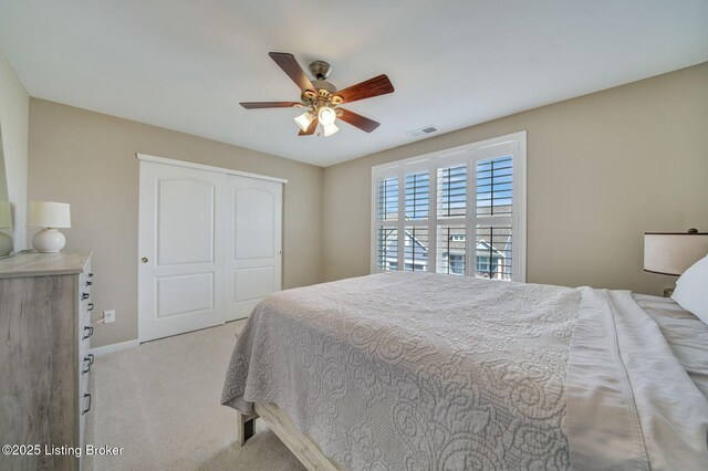 bedroom featuring ceiling fan, light carpet, visible vents, baseboards, and a closet