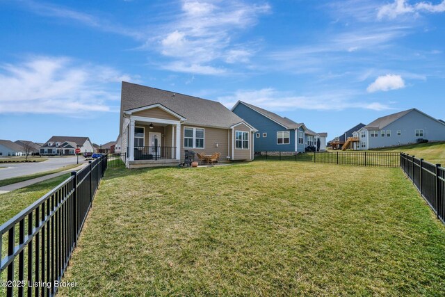 rear view of house with a fenced backyard, a residential view, and a lawn