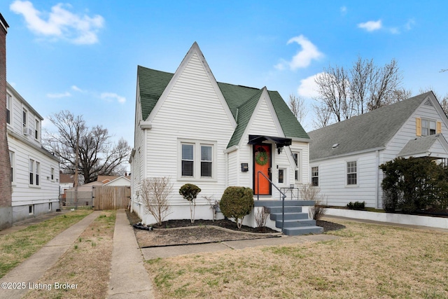 view of front facade featuring a front yard, fence, and roof with shingles