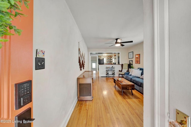 corridor featuring light wood-style floors and baseboards