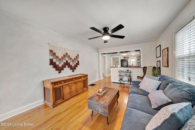 living room featuring light wood finished floors, baseboards, and a ceiling fan