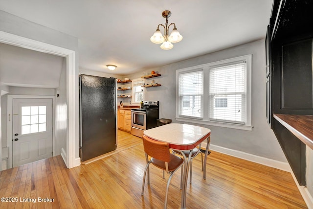 dining room featuring baseboards, light wood finished floors, a notable chandelier, and a healthy amount of sunlight