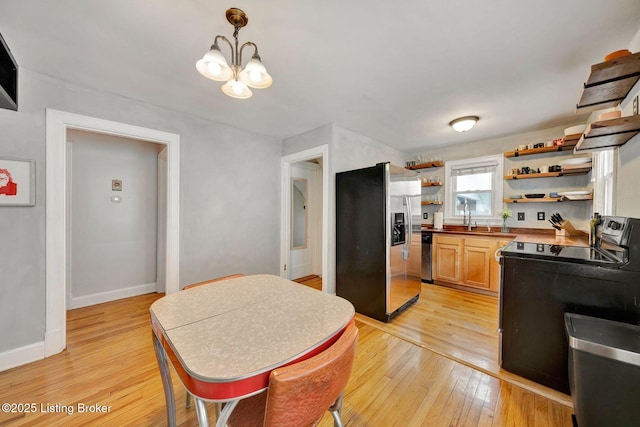 kitchen with light wood-style flooring, stainless steel appliances, a sink, baseboards, and open shelves