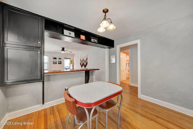 dining space featuring light wood-style floors, baseboards, and an inviting chandelier