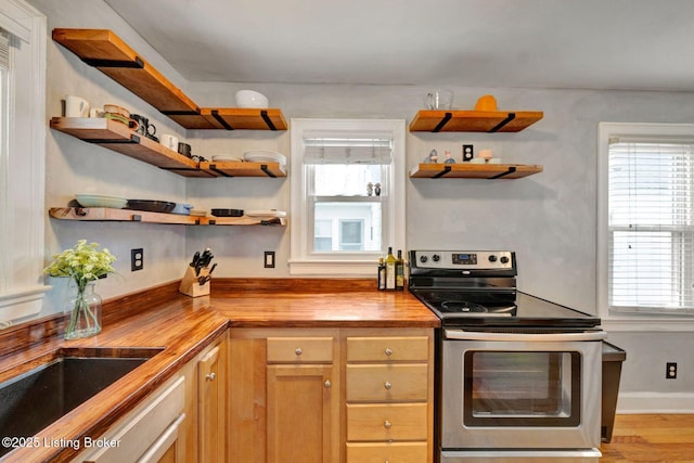 kitchen with open shelves, plenty of natural light, wooden counters, and stainless steel range with electric cooktop