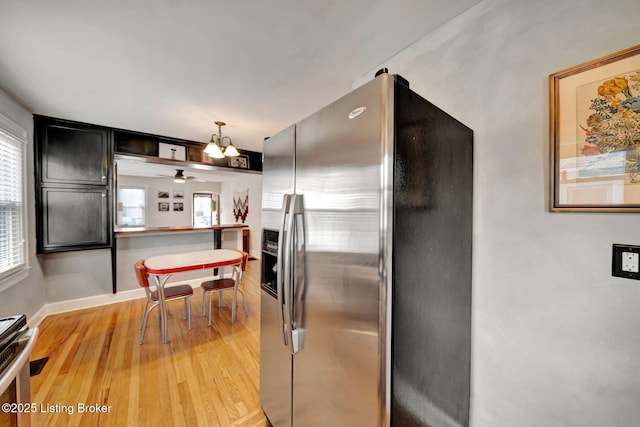 kitchen featuring a kitchen bar, hanging light fixtures, appliances with stainless steel finishes, light wood-style floors, and baseboards