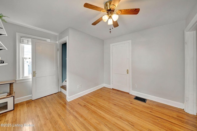 empty room featuring baseboards, visible vents, a ceiling fan, stairway, and light wood-style floors