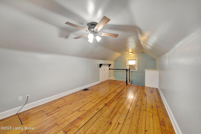 bonus room featuring lofted ceiling, wood-type flooring, visible vents, ceiling fan, and baseboards