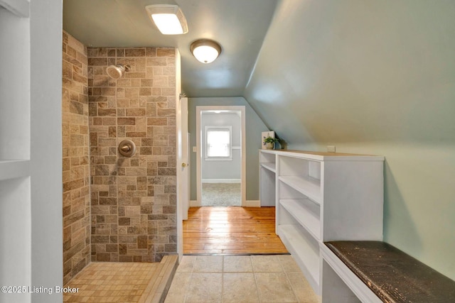 full bath with lofted ceiling, tiled shower, and baseboards