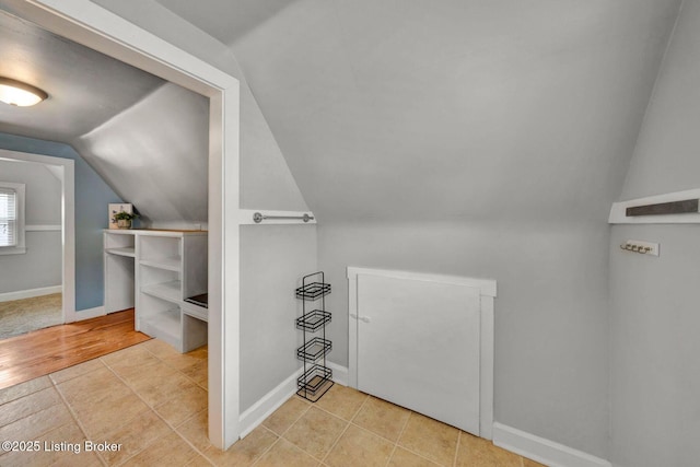 additional living space with light tile patterned floors, vaulted ceiling, and baseboards