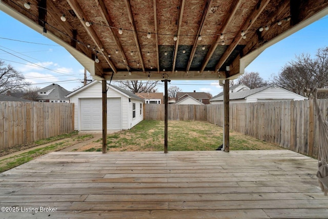 wooden deck featuring a fenced backyard, a detached garage, a lawn, and an outbuilding