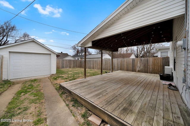 deck with driveway, a garage, a lawn, a fenced backyard, and an outbuilding