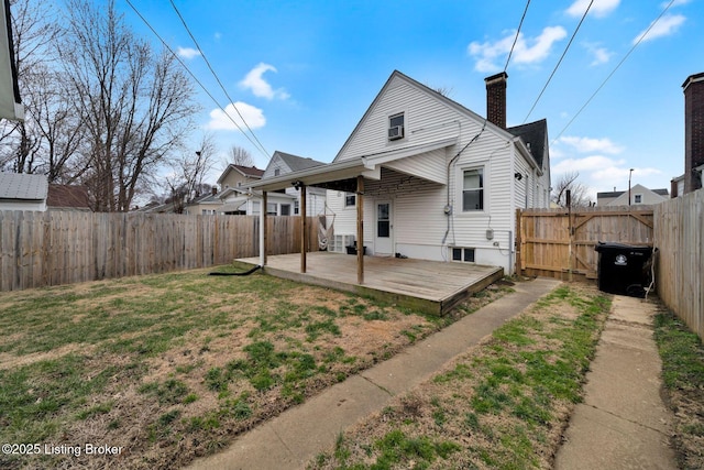 rear view of property featuring a patio area, a fenced backyard, a yard, and a chimney