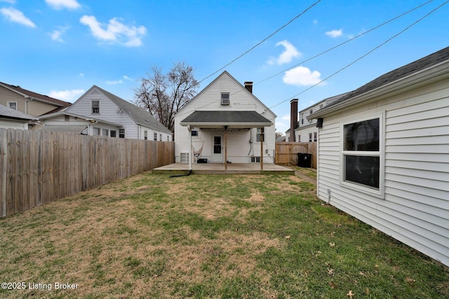 rear view of property featuring a patio area, a yard, and a fenced backyard