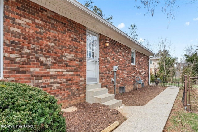 view of side of property featuring entry steps, brick siding, fence, and a gate