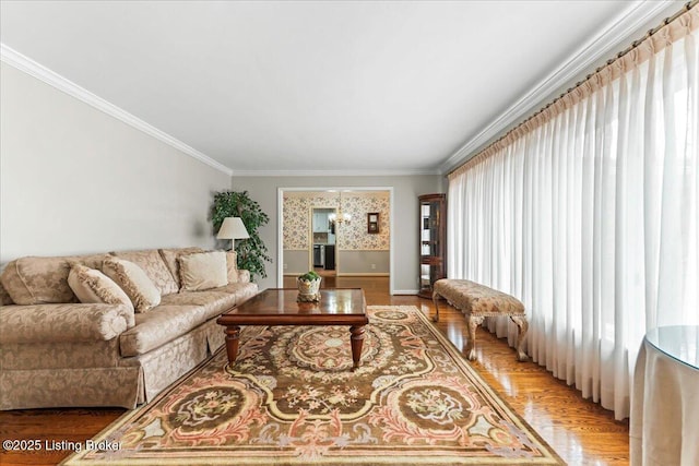 living room featuring crown molding, baseboards, a notable chandelier, and light wood-style floors