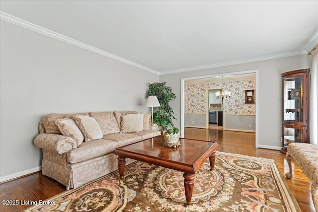 living area featuring baseboards, a notable chandelier, wood finished floors, and crown molding