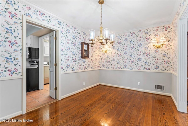 spare room with wallpapered walls, crown molding, visible vents, and a wainscoted wall