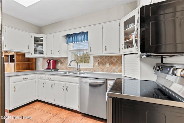 kitchen featuring light tile patterned floors, backsplash, appliances with stainless steel finishes, white cabinets, and a sink