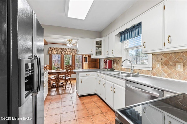 kitchen featuring light tile patterned floors, black fridge with ice dispenser, white cabinets, a sink, and dishwasher