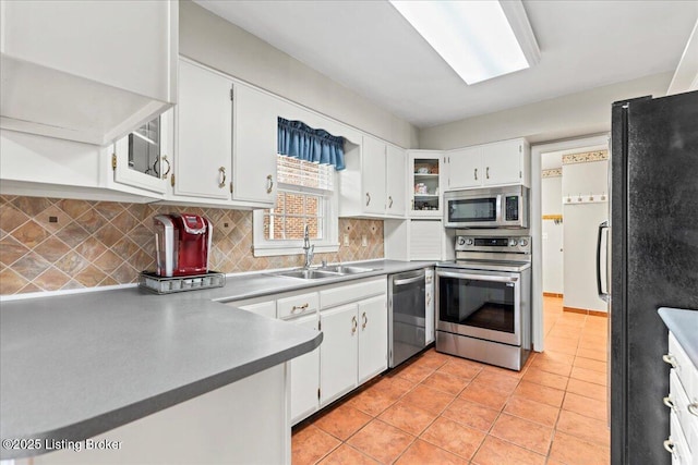 kitchen with decorative backsplash, appliances with stainless steel finishes, white cabinetry, a sink, and light tile patterned flooring