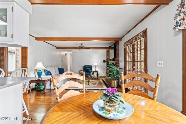 dining area featuring ceiling fan, ornamental molding, beamed ceiling, and wood finished floors