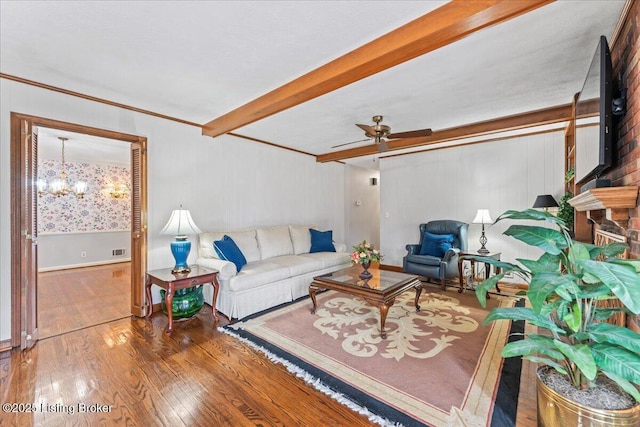 living area with beamed ceiling, hardwood / wood-style floors, and ceiling fan with notable chandelier