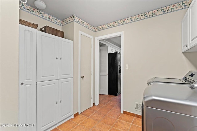 laundry room with light tile patterned floors, visible vents, baseboards, cabinet space, and washing machine and clothes dryer