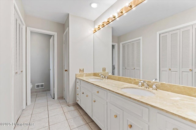 bathroom with double vanity, a closet, a sink, and toilet