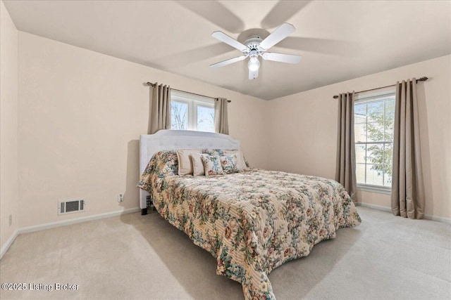 carpeted bedroom featuring a ceiling fan, visible vents, and baseboards