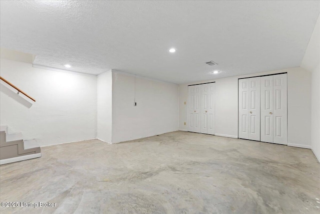 finished basement featuring stairs, a textured ceiling, and recessed lighting