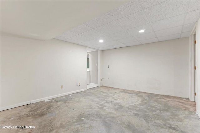 spare room featuring a paneled ceiling and unfinished concrete flooring