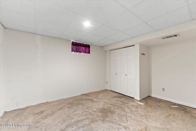 unfurnished bedroom with a closet, a drop ceiling, unfinished concrete flooring, and visible vents