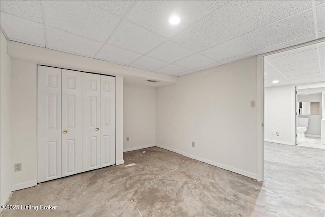 unfurnished bedroom featuring a paneled ceiling, visible vents, concrete floors, and baseboards