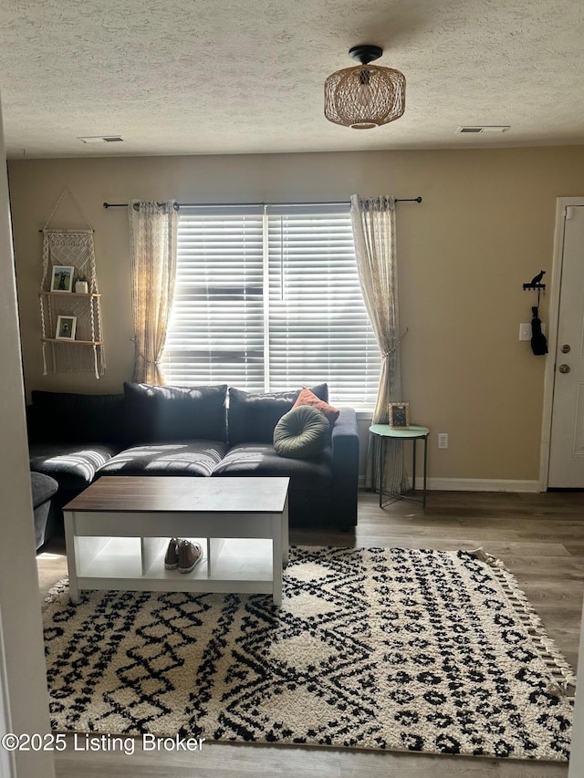 living room featuring visible vents, a textured ceiling, and wood finished floors