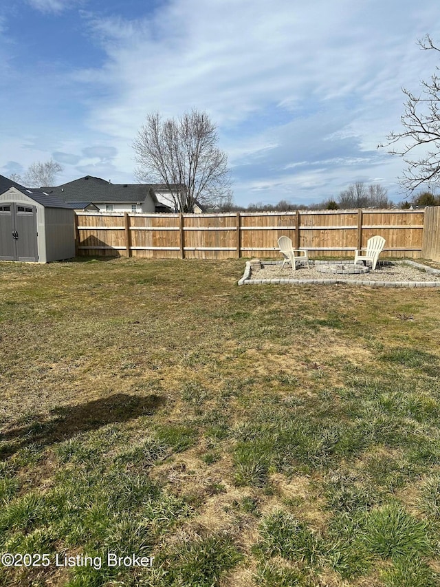 view of yard featuring an outbuilding, a fire pit, a storage unit, and a fenced backyard