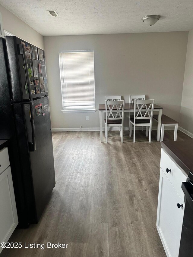 dining room with visible vents, baseboards, a textured ceiling, and wood finished floors