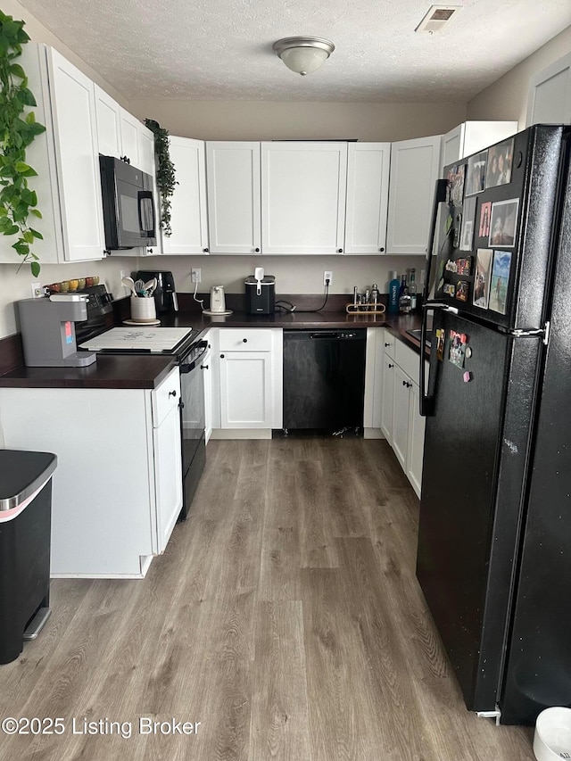 kitchen with dark countertops, black appliances, dark wood-style flooring, and a textured ceiling