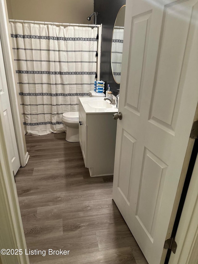 full bath featuring curtained shower, toilet, wood finished floors, and vanity