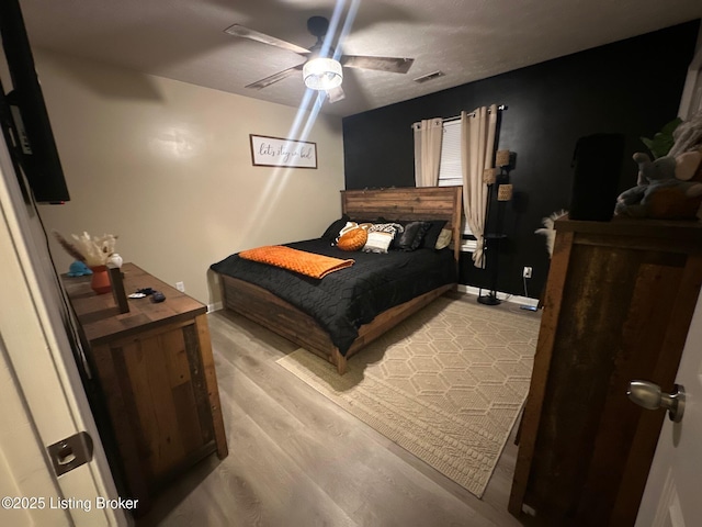 bedroom featuring visible vents, light wood-style flooring, baseboards, and ceiling fan