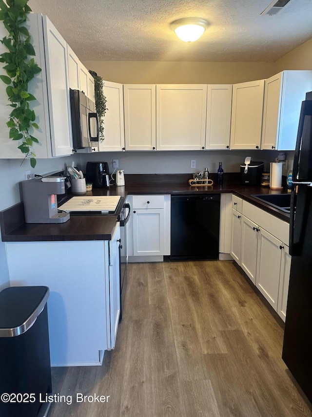 kitchen with white cabinetry, black appliances, and dark wood-style flooring