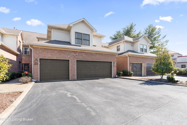 view of front of house featuring brick siding, an attached garage, a shingled roof, and aphalt driveway